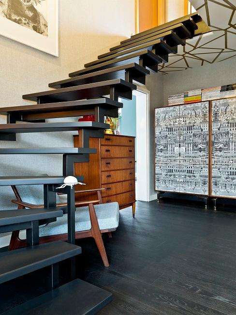 Schwarze offene Treppe über Lesebereich mit Kommode und Sessel