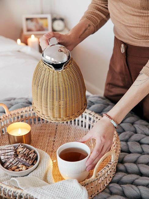 Frau schenkt Tee in Tasse ein