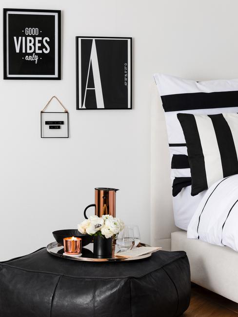 Dormitorio en blanco y negro, cuadros negros, ropa de cama negra y flores