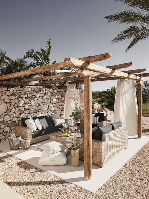 Houten pergola heading Houten pergola in ibiza stijl met zandkleur meubels tegen stenen muur