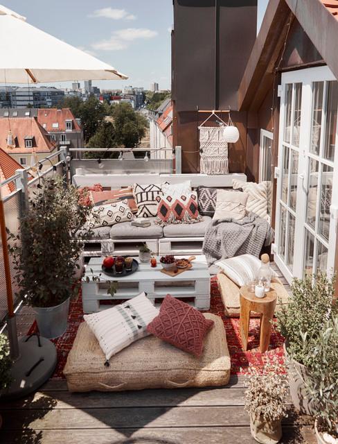 Balkon z kanapą zrobioną z palet, roślina oraz dekoracjami