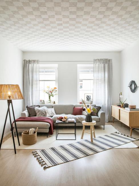Salon w stylu boho, z narożną, rozkładaną kanapą, czarnym stolikiem kaowowym, drewnianym stołkiem oraz fioletowymi dekoracjami