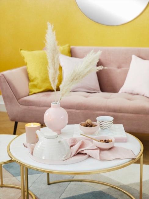 Sofá rosa de terciopelo con cojines de seda y pared de fondo color mostaza