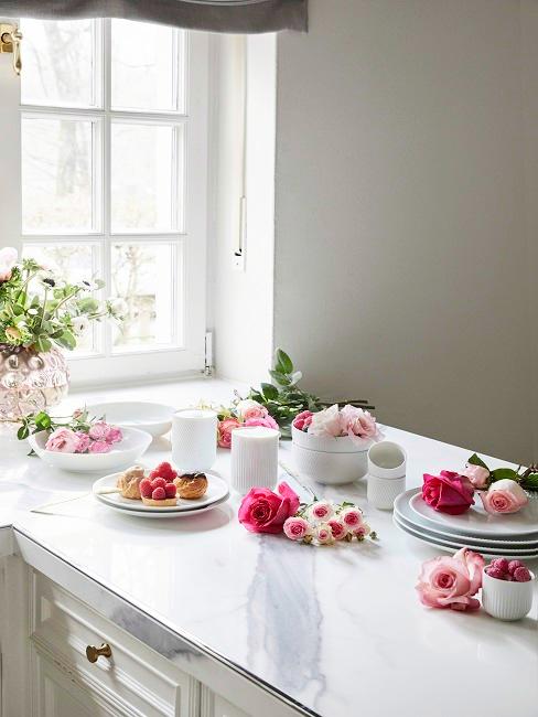 Décorer avec des roses Roses des différentes nuances de la couleur rose étalées sur l'îlot blanc de la cuisine