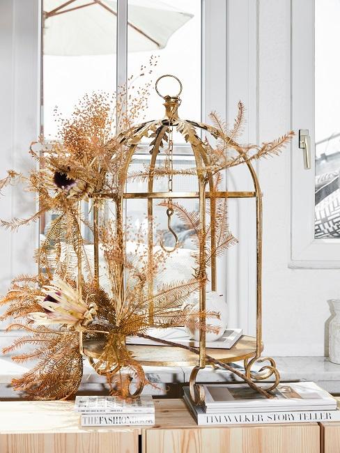 Vogelkäfig-Deko auf dem Fensterbrett mit Blumen in Gold
