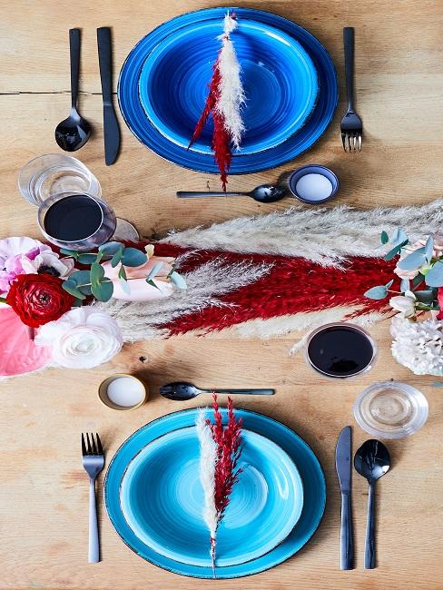 Gedeckter Tisch mit blauen Tellern, Besteck und Gläsern