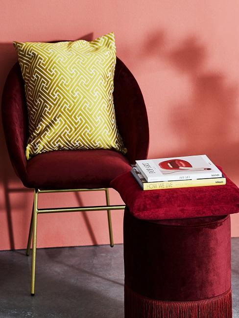 Roter Samtstuhl mit gelbem Kissen neben Pouf