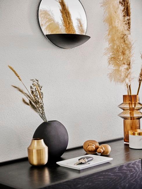 Vasen mit Sträuchern auf dunklem Sideboard