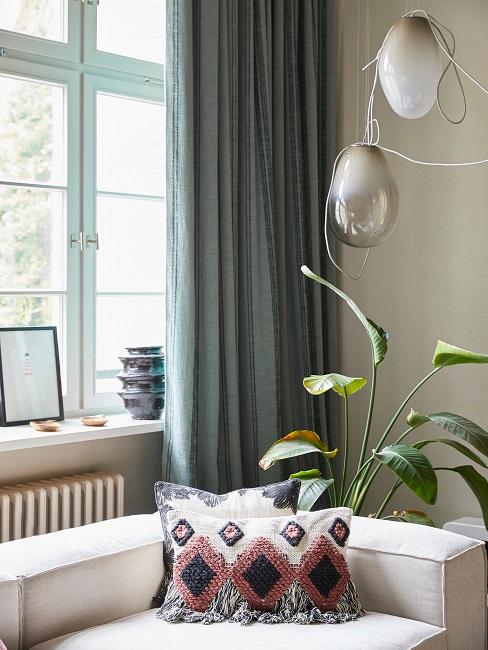 Helle Couch vor großem Fenster mit Vorhang