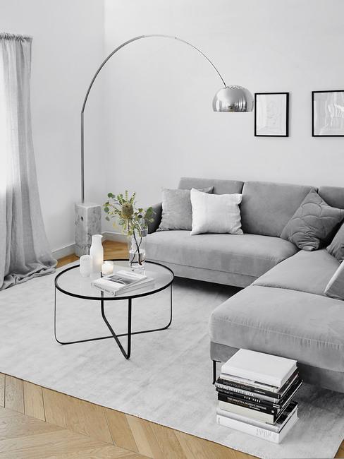 Szara sofa i jasny dywan oraz lampa łukowa w stylu minimalistycznym