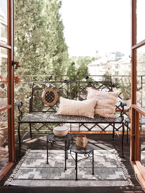 Balkon z dwuosobową ławką z poduszkami oraz dwoma, małymi stolikami pomocnicznymi