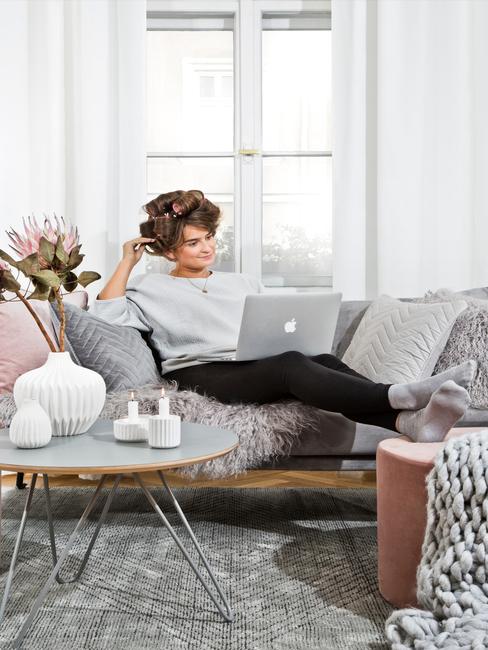Home office Kobieta siedząca na sofie z wielona poduszkami przy okrągłym stoiku w domowym biurze