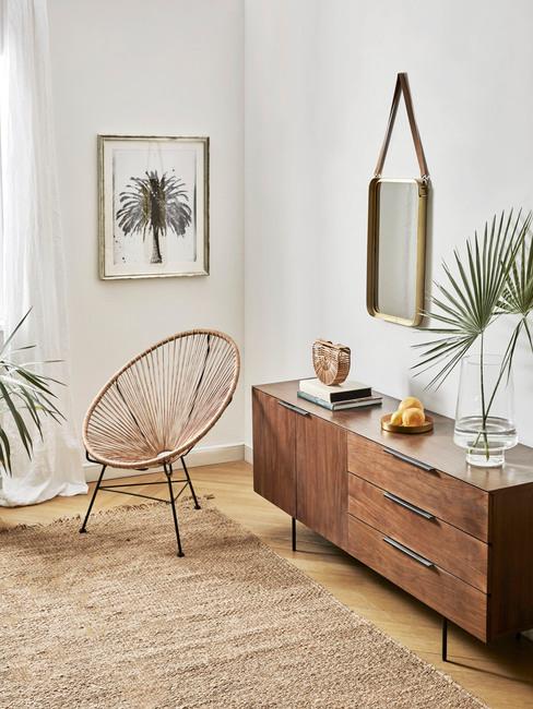 Salon boho Salon w stylu boho z drewniana komodą, plecionym krzesłem roślinami oraz ozdobami na ścianie