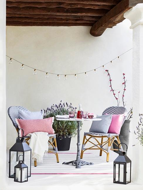 Terrasse mit rundem Tisch und zwei Stühlen mit viel Deko