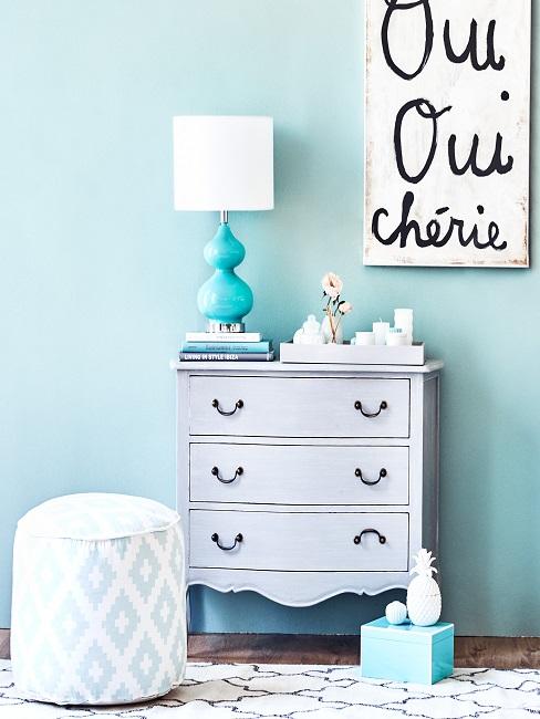 Blauer Flur mit weißer Kommode, Wandbild und Pouf mit Deko