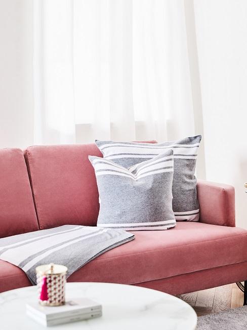 Rosa samt Couch mit grauen Kissen
