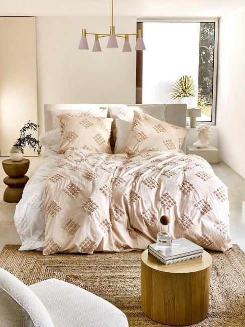 Bett in hellem Schlafzimmer mit beige und weißer Bettdecke