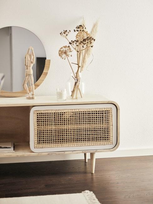 Salon boho Komoda z plecionymi fronatmi, a niej wazon z suszonymi kwiatami