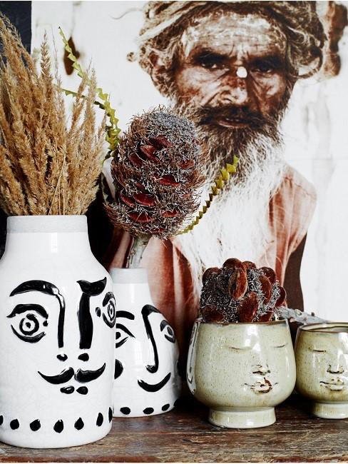 Vases with painted faces and dried flowers
