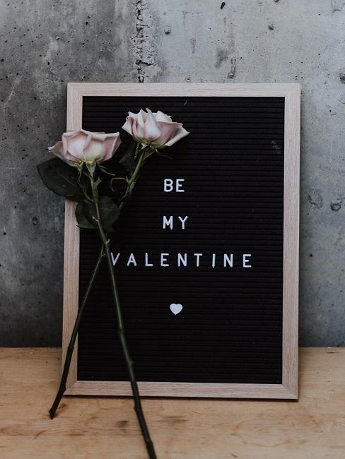Two roses in front of a letter board