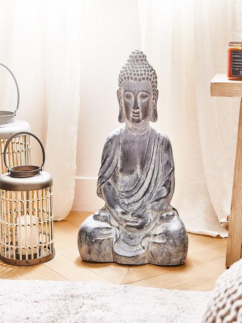 Laternen neben großer Buddha Figur im Bad