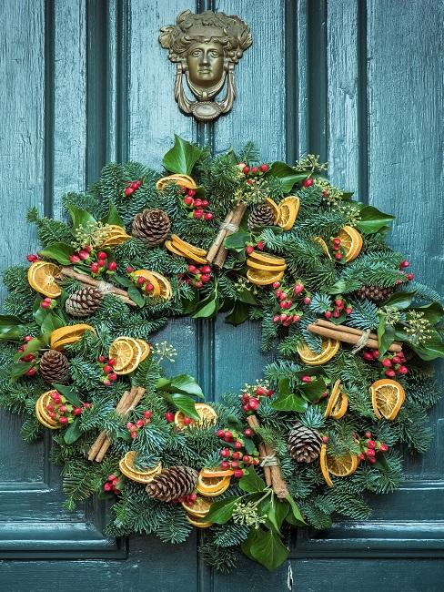 Door wreath with pine cones and dried oranges on a green door
