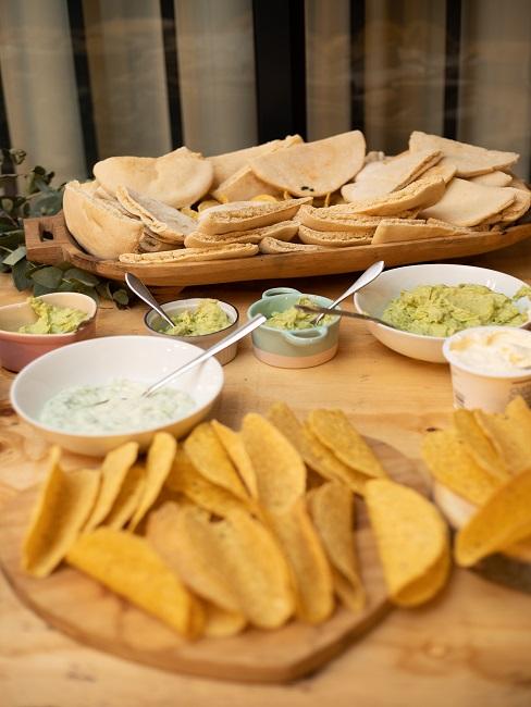 Tisch mit Brot, verschiedenen Dips und Tacos