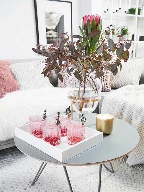 Verres à whisky roses sur table d'appoint grise avec bouquet de fleurs