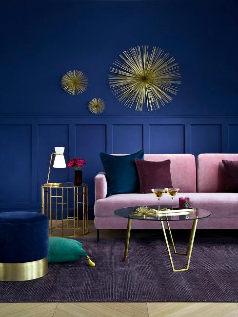 Sofá rosa con cojines de colores y pared de fondo azul eléctrico oscuro