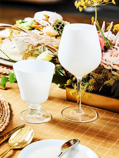 Weiße Gläser auf dem Tisch vor Blumendeko