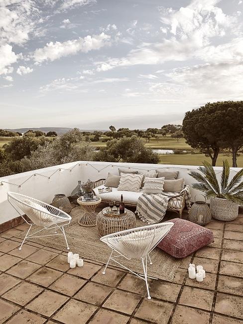 Dachterrasse mit Loungesofa mit vielen Kissen in Beige, Acapulco Chairs, Bodenkissen und Beistelltischen aus Rattan