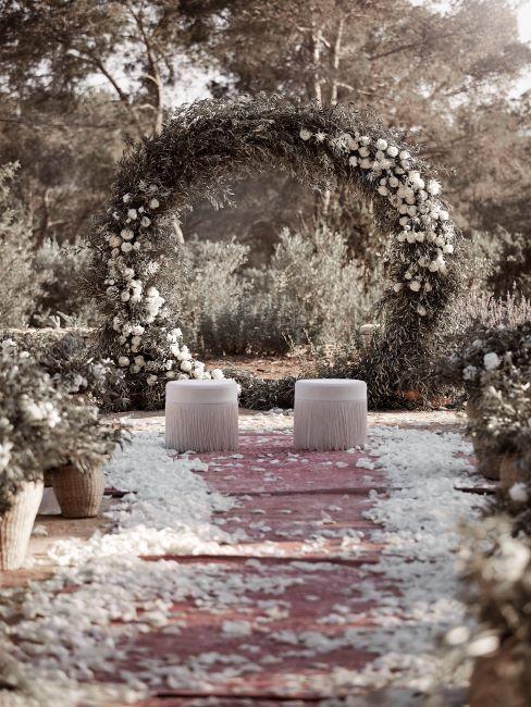 Accessoires de mariage exterieur, grande couronne fleurie en guise d'autel, devant deux poufs blancs