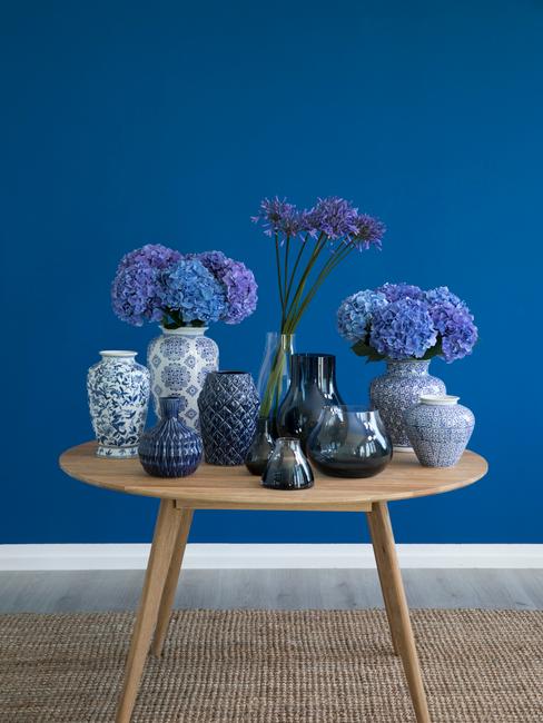 Bleu saphir Mur bleu avec table en bois scandinave remplis de vases et de fleurs bleues