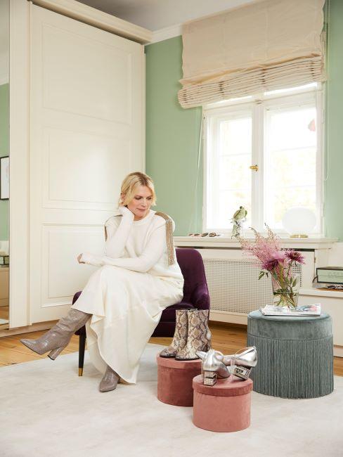 rangement-pour-chaussures femme assise sur un pouf dans un salon pastel, mur vert, poufs sur lesquels sont posees les chaussures design
