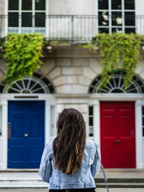 facade-house Femme de dos devant deux façades de maisons porte rouge et porte bleue