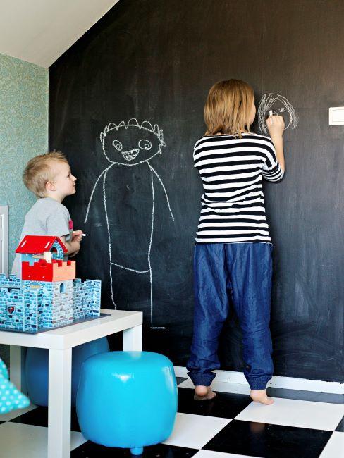 Salle de jeu Deux petits garçons en train de dessiner sur un mur fait d'un grand tableau noir