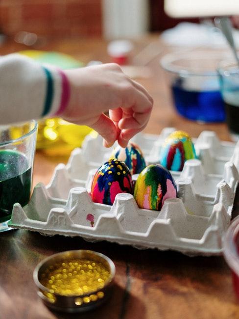 Bricolage de Pâques Main d'enfant qui décore des œufs de Pâques