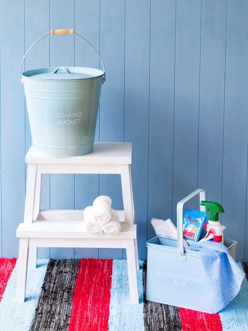 Grand nettoyage Mur bleu, tapis rayé, tabouret blanc et accessoires de nettoyage