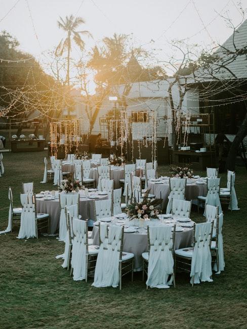 Réception de mariage dans un jardin Tables mariage rondes decorees de blanc et guirlandes lumineuses