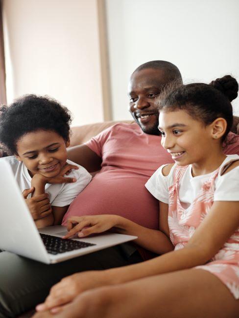 films-pour-enfants-a-regarder-en-famille un pere regarde un ordinateur portable avec ses deux enfants