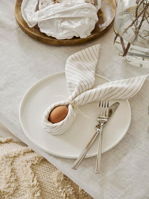 PaashaasMaken5 Ingezoomde tafel met wit tafelkleed en wit servies met paashaas gemaakt van een ei met servet
