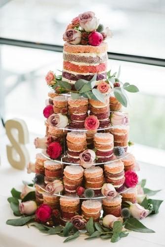 Tort weselny wykonany z babeczek w stylu naked cake wraz z kwiatami jako dekoracja