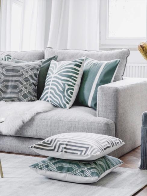 Wohnzimmer Salbeigrün Wohnzimmer in grau mit salbeigrünen Akzenten in form von gemusterten salbeigrünen Kissen und einem Fransen Hocker mit Blumendeko