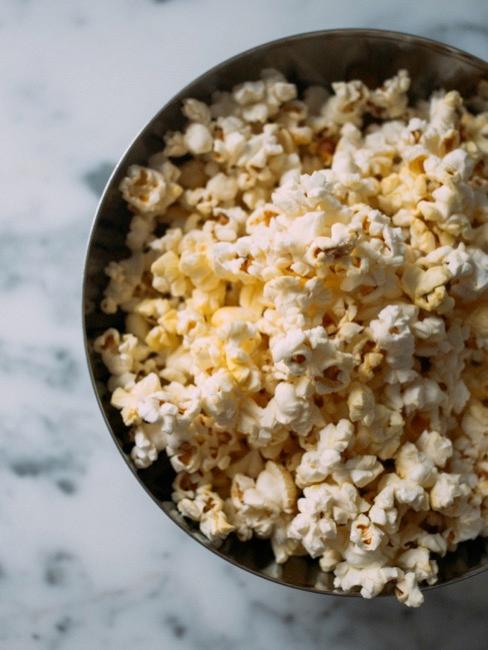 Serie tv da vedere Popcorn per la notte di film in una ciotola su tavolino in marmo