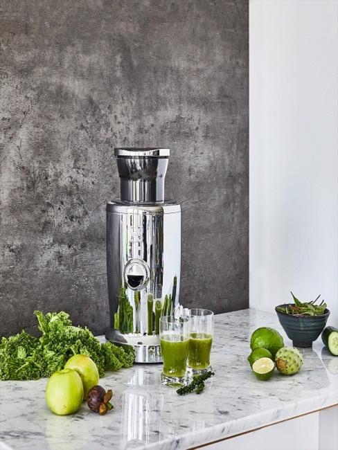 Silberne Saftpresse mit Limetten in Küche