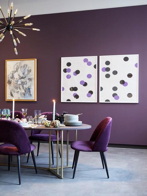 Tavolo rotondo allungabile nella sala da pranzo in massimalismo con sedie imbottite e una parete viola.