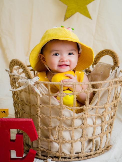 Babykamer-okergeel-hoofdfoto baby in geel hoedje in rotan mandje