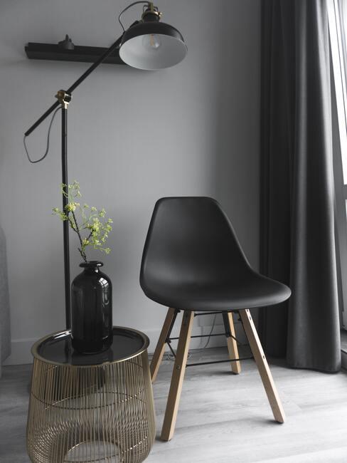 Krzesło projektu Eames w czarnym kolorze na tle szarej ściany