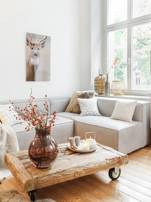 Jasna sofa w salonie w stylu rustykalnym, drewniany stolik kawowy