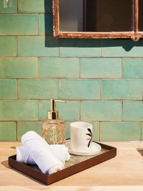Close-up badkamer met wandtegels in turquoise en dienblad met handdoeken en decoratieve objecten